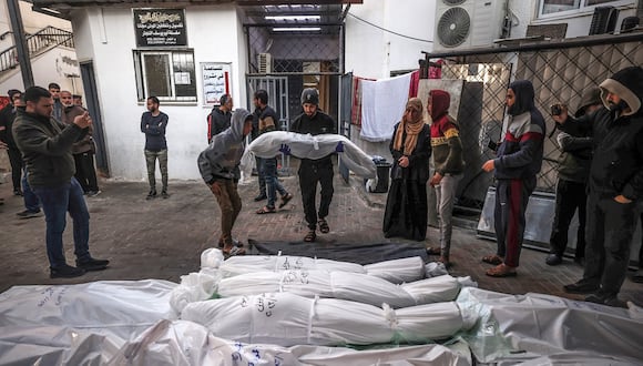 Cuerpos envueltos de personas asesinadas en Rafah durante el bombardeo israelí en la franja del sur de Gaza, se colocan fuera del Hospital Al-Najar el 29 de diciembre de 2023 (Foto de AFP)