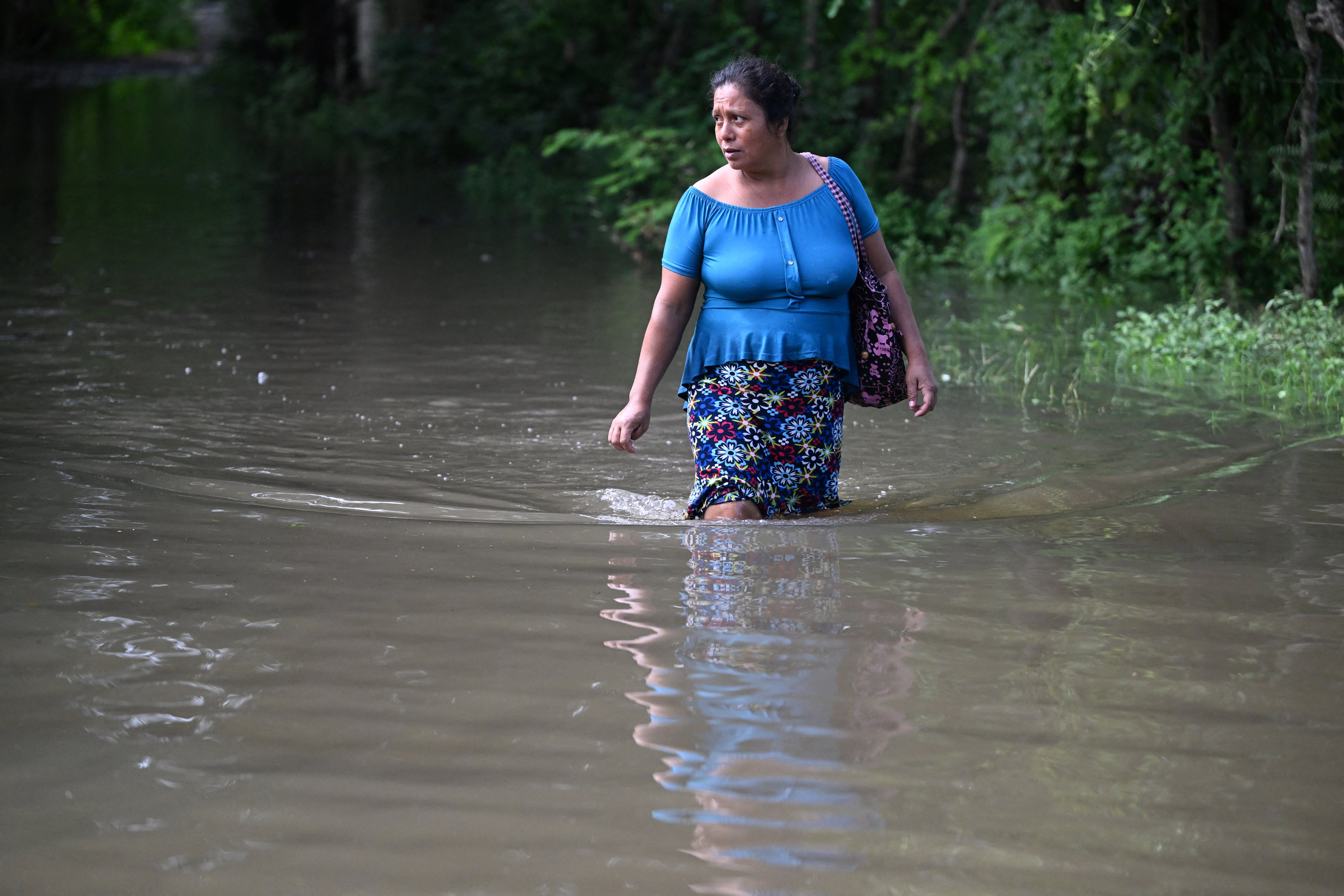 Una mujer camina por una calle inundada después del paso de la tormenta tropical Pilar en la aldea de Los Ángeles, en Zacatecoluca, El Salvador, el 1 de noviembre de 2023. (Foto de Marvin RECINOS / AFP).