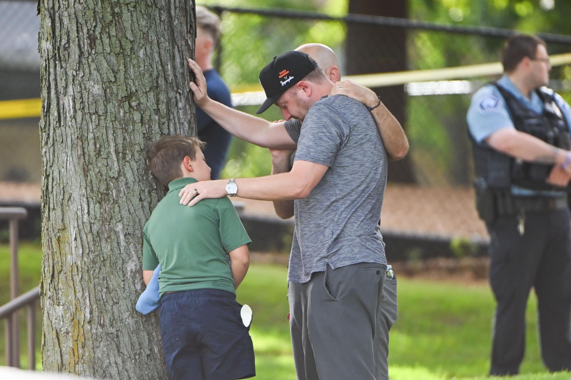Un adulto y un niño salen mientras la policía responde a un tiroteo en la Escuela Católica Annunciation en Minneapolis, Minnesota, Estados Inidos. (EFE/EPA/CRAIG LASSIG).