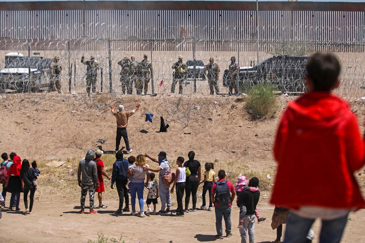 Migrantes que intentan ingresar a Estados Unidos a través de una cerca de alambre de púas a lo largo del Río Grande, en la frontera con Ciudad Juárez, estado de Chihuahua, México, el 13 de mayo de 2024. (Foto de HERIKA MARTINEZ / AFP)