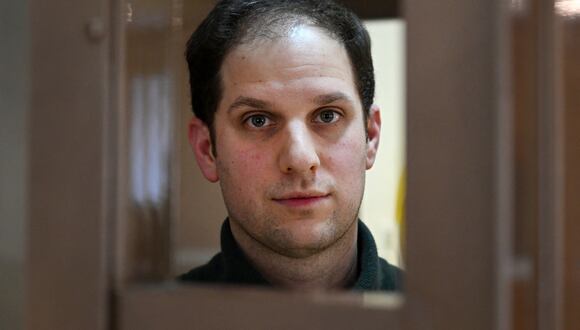 El periodista estadounidense Evan Gershkovich, arrestado por cargos de espionaje, mira desde el interior de la jaula de los acusados ​​antes de una audiencia en Moscú, Rusia, el 20 de febrero de 2024. (Foto de NATALIA KOLESNIKOVA / AFP).