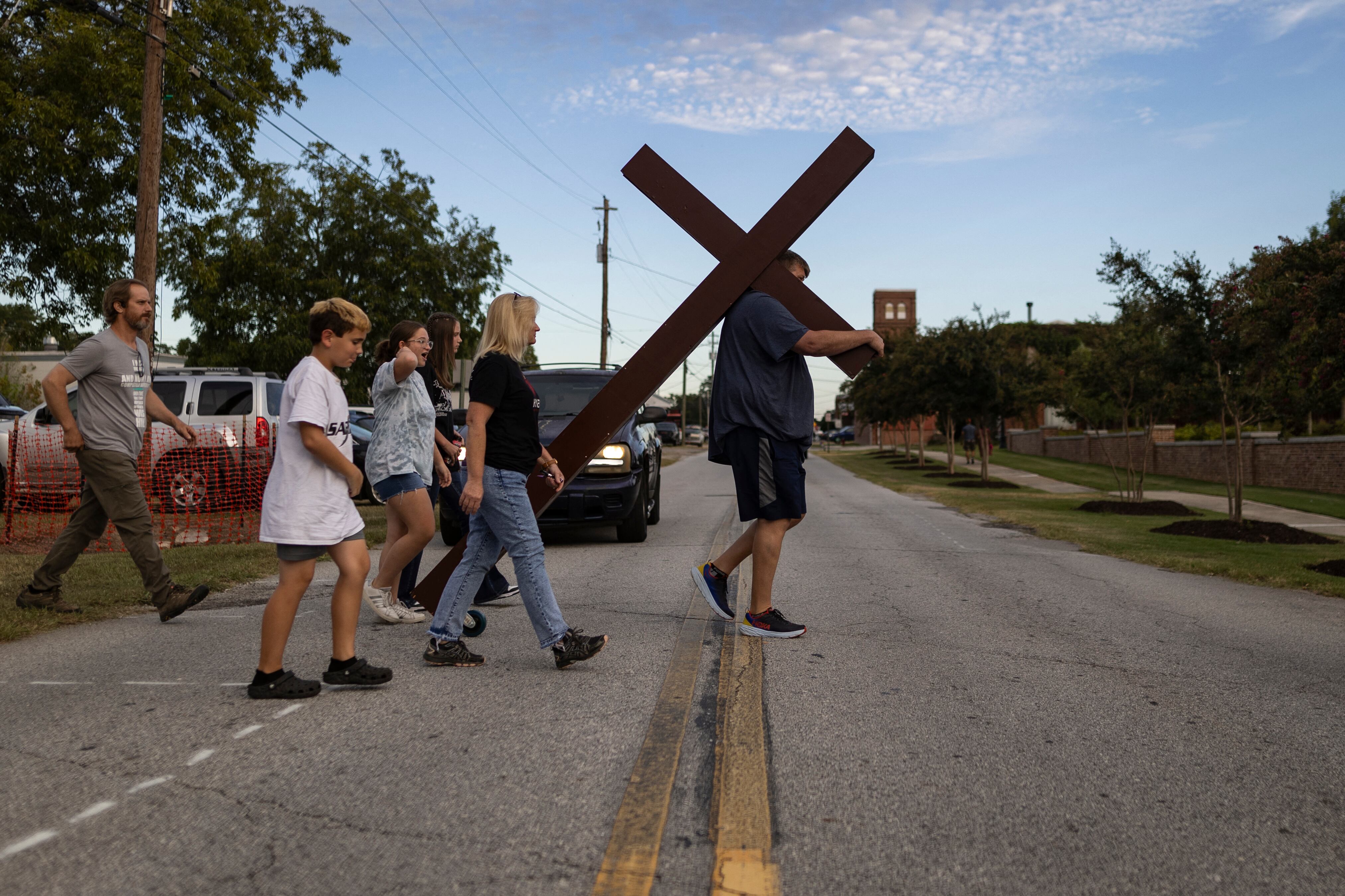 Un hombre lleva una gran cruz a una vigilia por el tiroteo en la escuela secundaria Apalachee en Jug Tavern Park en Winder, Georgia, el 4 de septiembre de 2024. (Foto de CHRISTIAN MONTERROSA / AFP)
