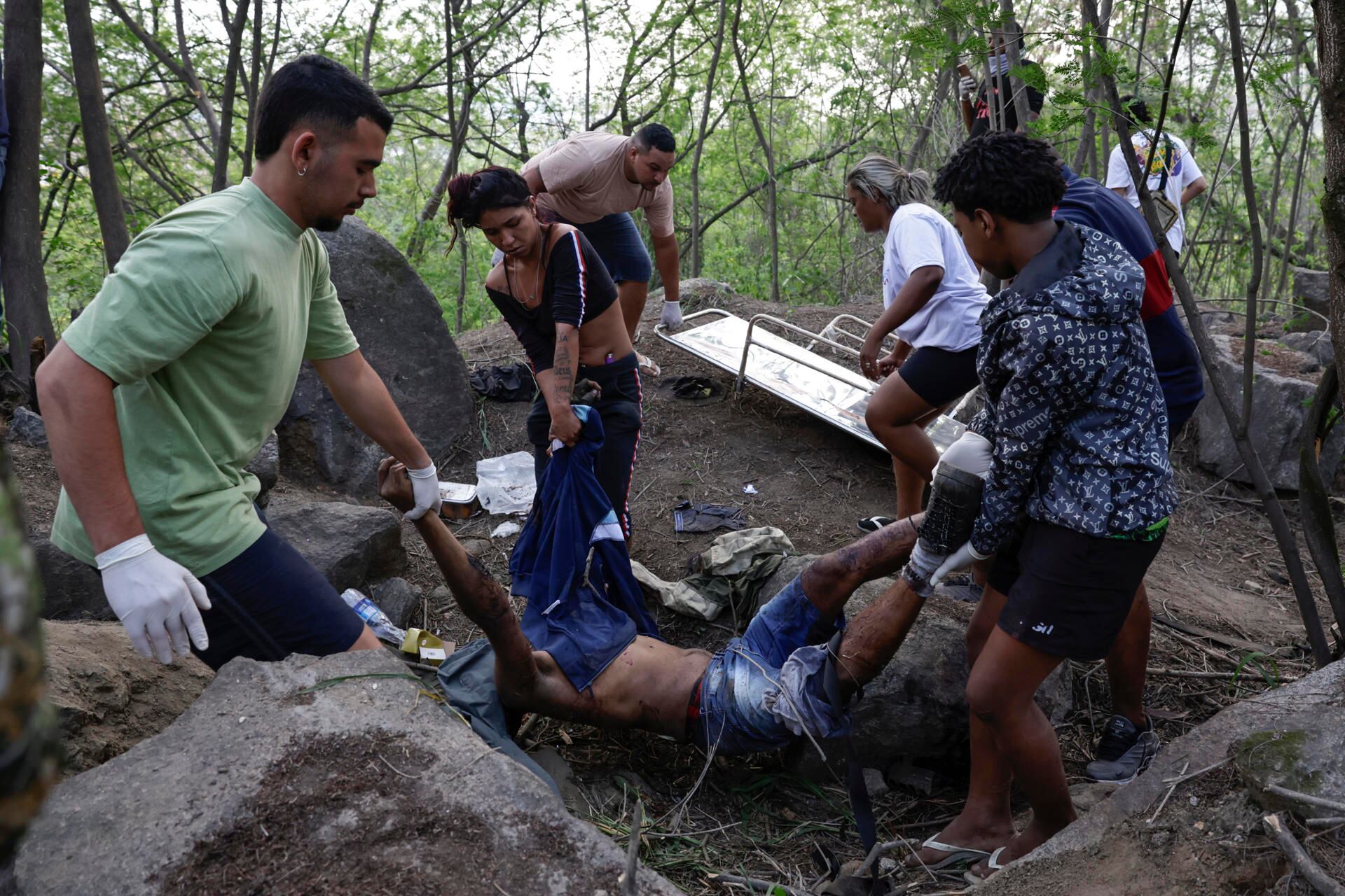Personas retiran un cuerpo sin vida de una zona boscosa en la favela Vila Cruzeiro, en Río de Janeiro. (EFE/ André Coelho).
