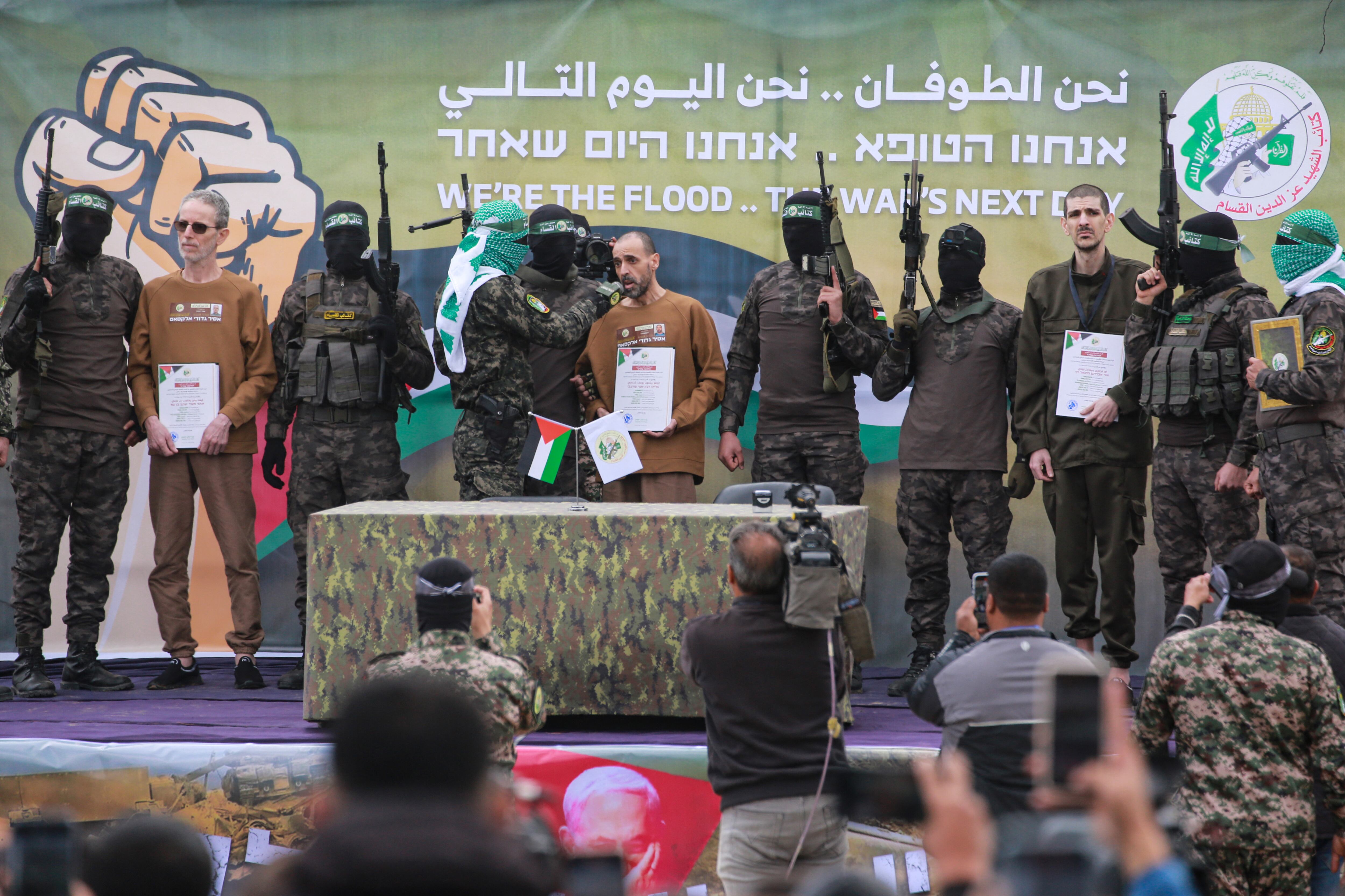 Combatientes palestinos de Hamas escoltan a los rehenes israelíes (de izq. a der., con certificados en la mano) Ohad Ben Ami, Or Levy y Eli Sharabi en un escenario antes de entregarlos a un equipo de la Cruz Roja en Deir el-Balah, en el centro de Gaza. (Foto de Bashar TALEB / AFP)