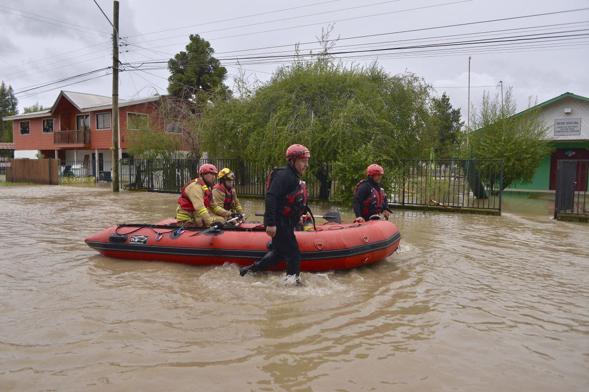 Los bomberos evacuan a los residentes atrapados en la ciudad inundada de Cabrero, en la región central del Bío Bío de Chile, el 21 de agosto de 2023, después de que las fuertes lluvias provocaran el desbordamiento del río Laja (Foto: Guillermo Salgado / AFP)