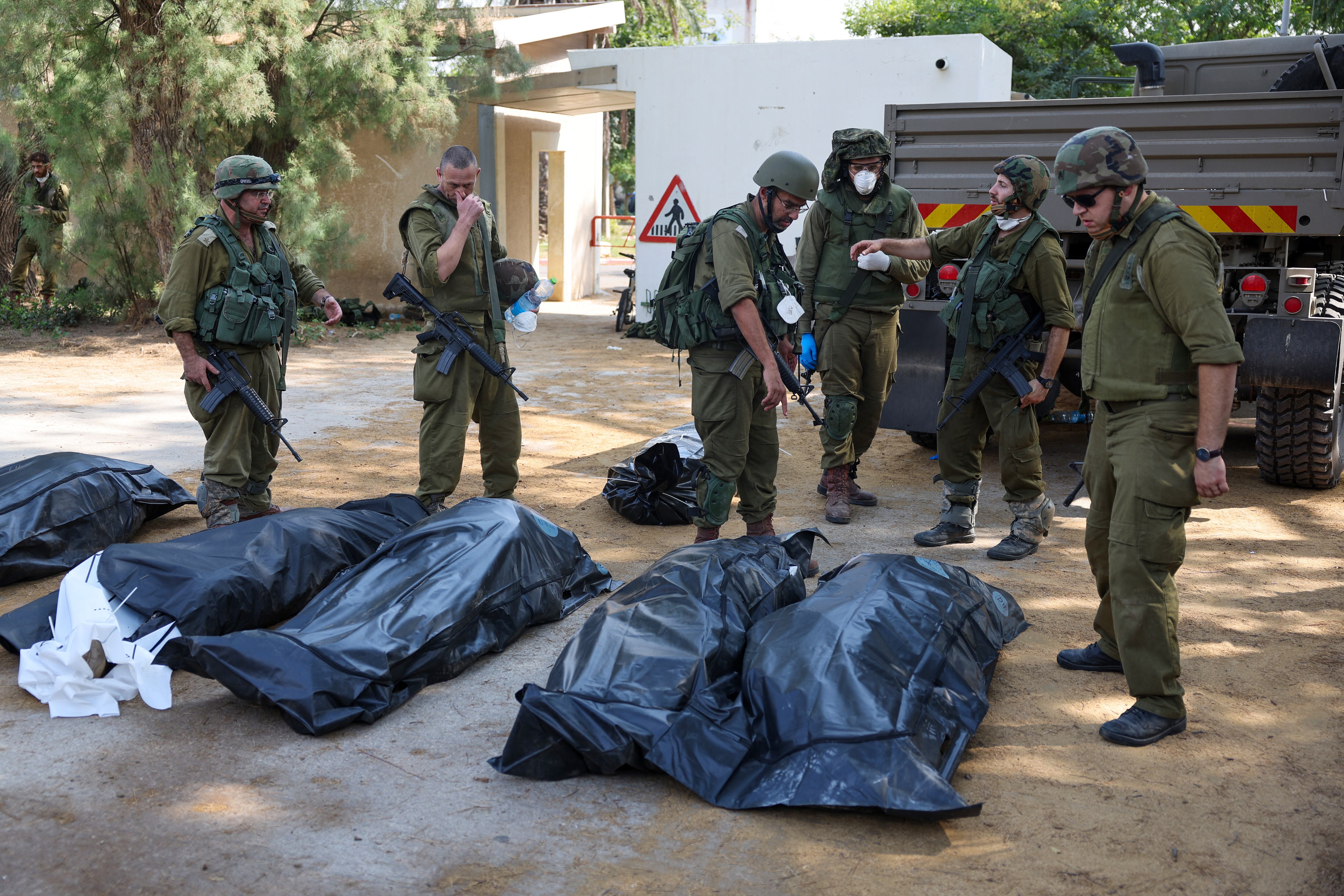 Soldados israelíes se preparan para retirar los cuerpos de sus compatriotas, muertos durante un ataque de militantes palestinos de Hamás en Kfar Aza, al sur de Israel. (Foto de JACK GUEZ / AFP).
