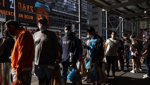 Un grupo de migrantes espera en fila después de llegar desde Texas, afuera de la Terminal de Autobuses de la Autoridad Portuaria para recibir asistencia humanitaria el 10 de agosto de 2022 en Nueva York. (Foto de Yuki IWAMURA / AFP)