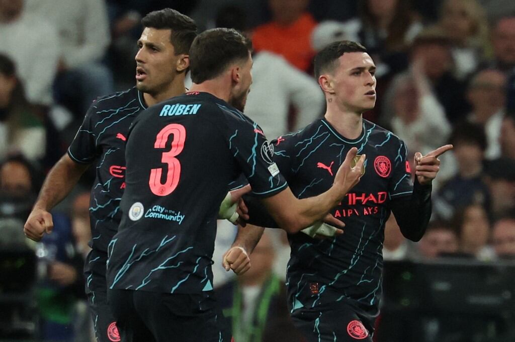 Manchester City's English midfielder #47 Phil Foden (R) celebrates with teammates after scoring his team's second goal during the UEFA Champions League quarter final first leg football match between Real Madrid CF and Manchester City at the Santiago Bernabeu stadium in Madrid on April 9, 2024. (Photo by Pierre-Philippe MARCOU / AFP)