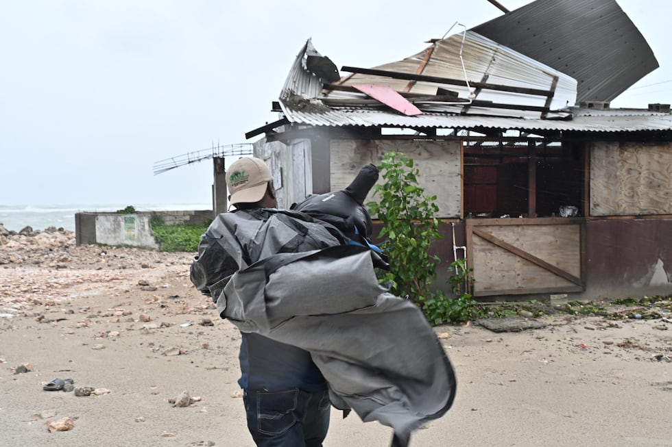Un hombre carga una lona para cubrir el techo de una casa antes del paso del huracán Melissa este lunes en la playa pesquera de Hellshire, en Portmore, Jamaica. (EFE/Rudolph Brown).