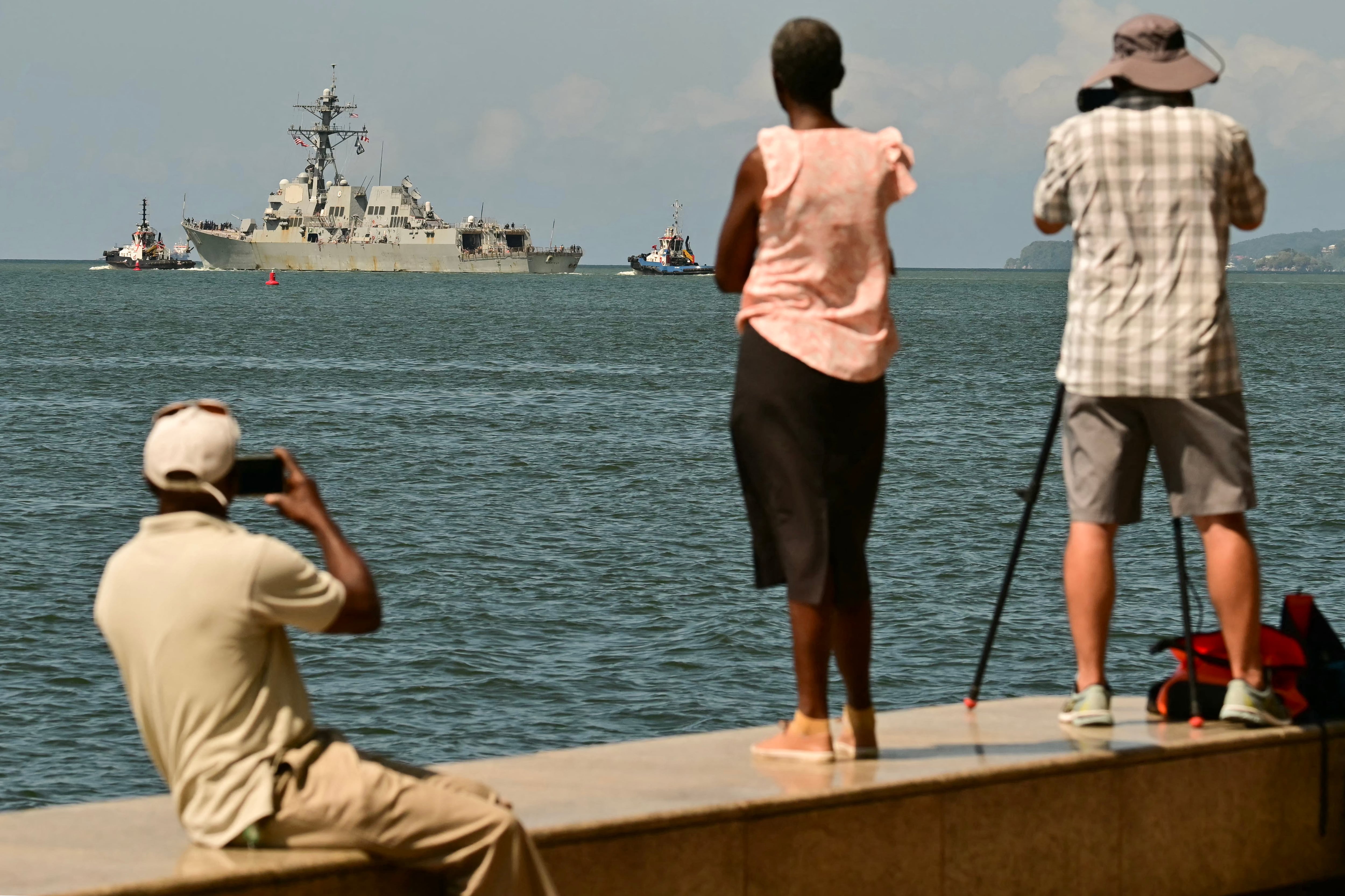La gente observa y toma fotografías del USS Gravely, un buque de guerra de la Armada de los Estados Unidos, que zarpa del Puerto de Puerto España el 30 de octubre de 2025. (Foto de MARTIN BERNETTI / AFP).