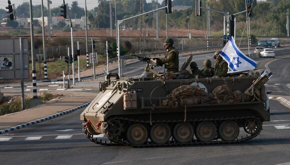 Las fuerzas israelíes cruzan una carretera principal en su vehículo blindado de transporte de personal (APC) mientras se despliegan tropas adicionales cerca de la ciudad sureña de Sderot el 8 de octubre de 2023. (Foto de Menahem KAHANA / AFP).