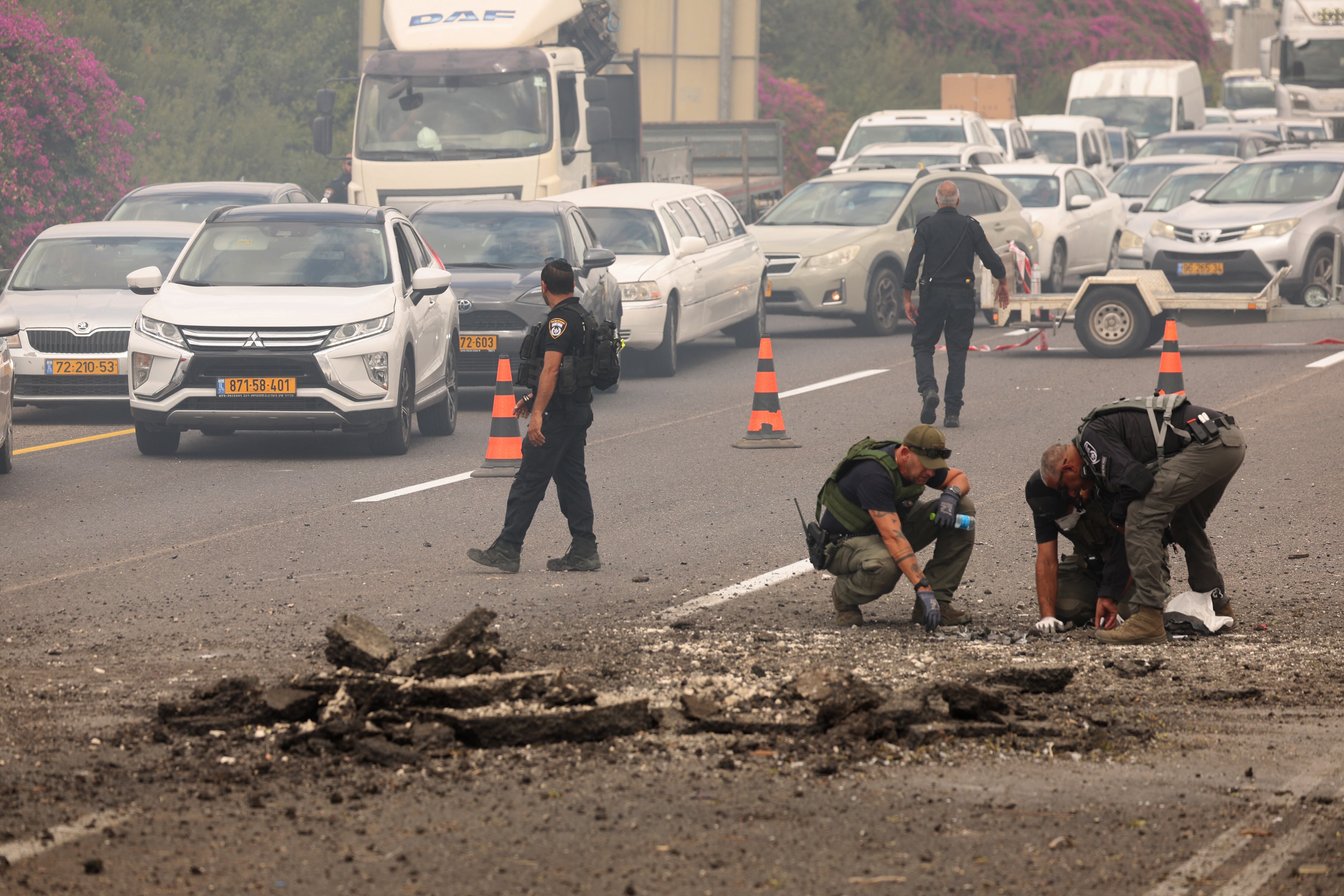 Miembros de las fuerzas de seguridad israelíes inspeccionan el lugar del impacto de un cohete lanzado desde el Líbano, en el cruce de Horeshim, en el centro de Israel, el 1 de octubre de 2024. (Foto de Jack GUEZ / AFP)