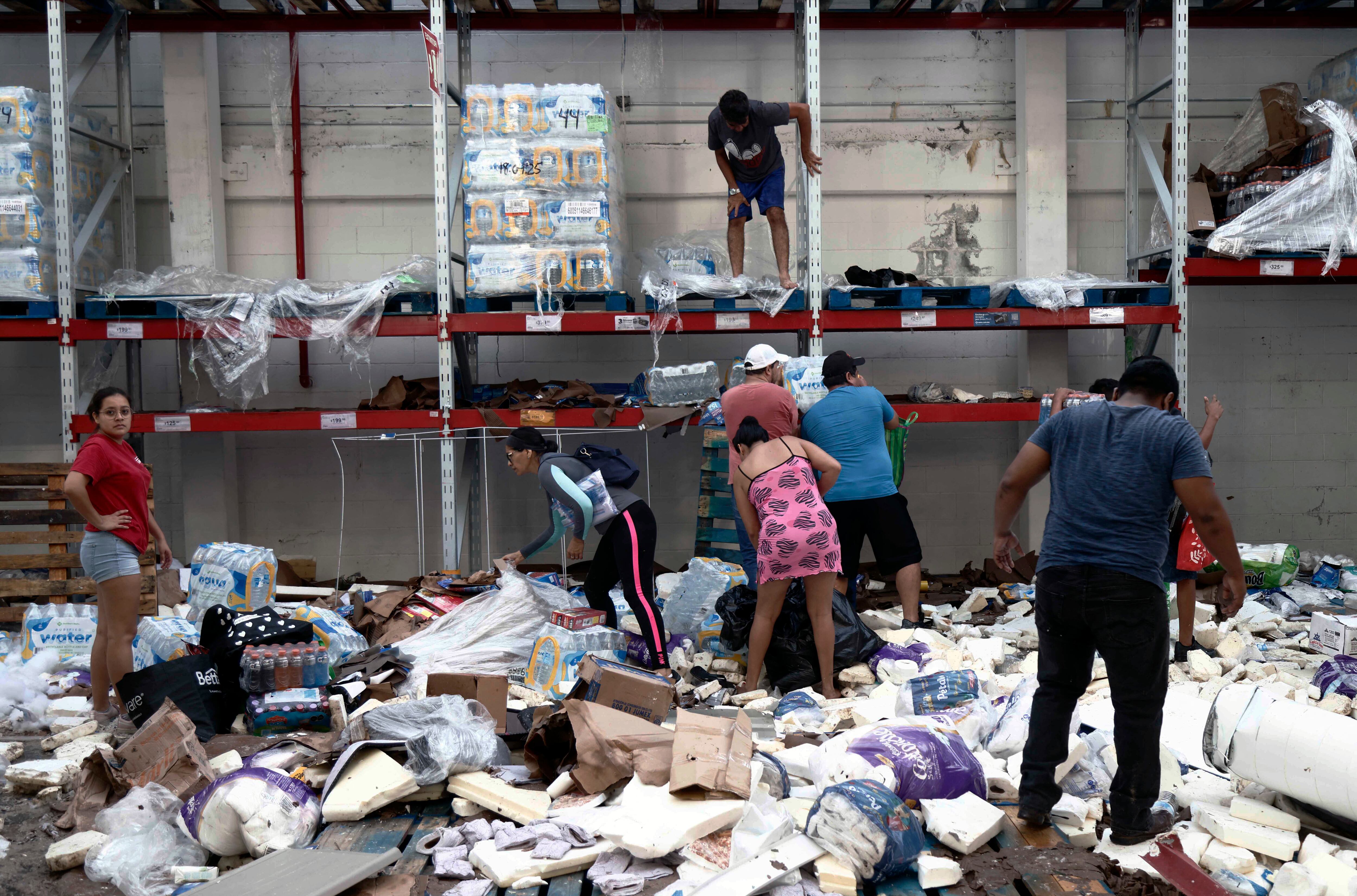 La gente recoge comestibles en un supermercado saqueado después del paso del huracán Otis en Acapulco. (Foto de RODRIGO OROPEZA/AFP).
