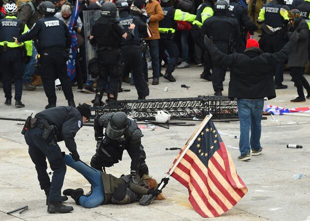 La policía detiene a una persona mientras los partidarios del presidente estadounidense Donald Trump protestan frente al Capitolio de los Estados Unidos el 6 de enero de 2021 en Washington, DC. (Foto de ROBERTO SCHMIDT / AFP)