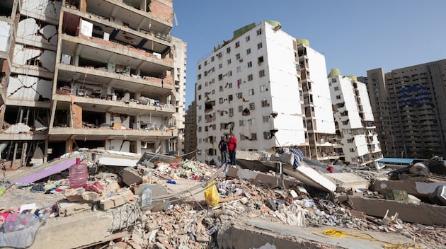 Personas caminan entre escombros de edificios afectados por terremotos, en Catia La Mar, Venezuela, el 25 de junio de 2026. (Ronald Peña R / EFE)