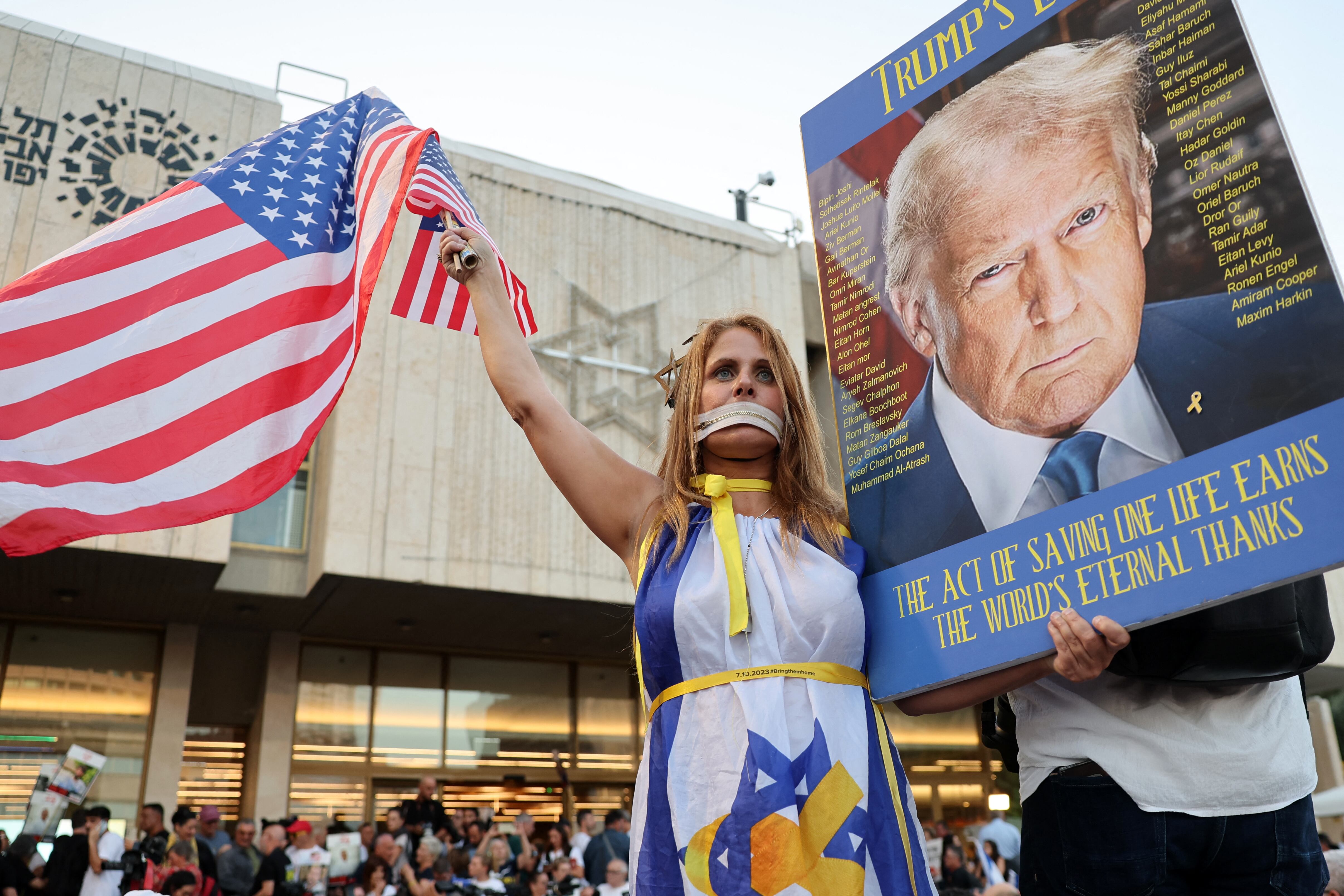 Una mujer, envuelta en una bandera israelí, ondea la de Estados Unidos y sostiene una foto de Donald Trump durante una reunión frente al Museo de Arte de Tel Aviv, el 11 de octubre de 2025. (Foto de Jack GUEZ / AFP).