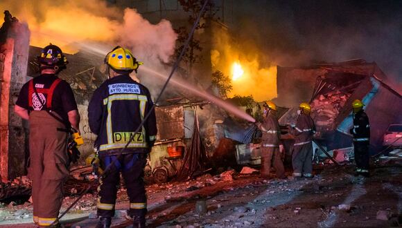 Bomberos trabajan para extinguir un incendio luego de una explosión en un establecimiento comercial en San Cristóbal, República Dominicana, el 14 de agosto de 2023. (Foto de AFP)