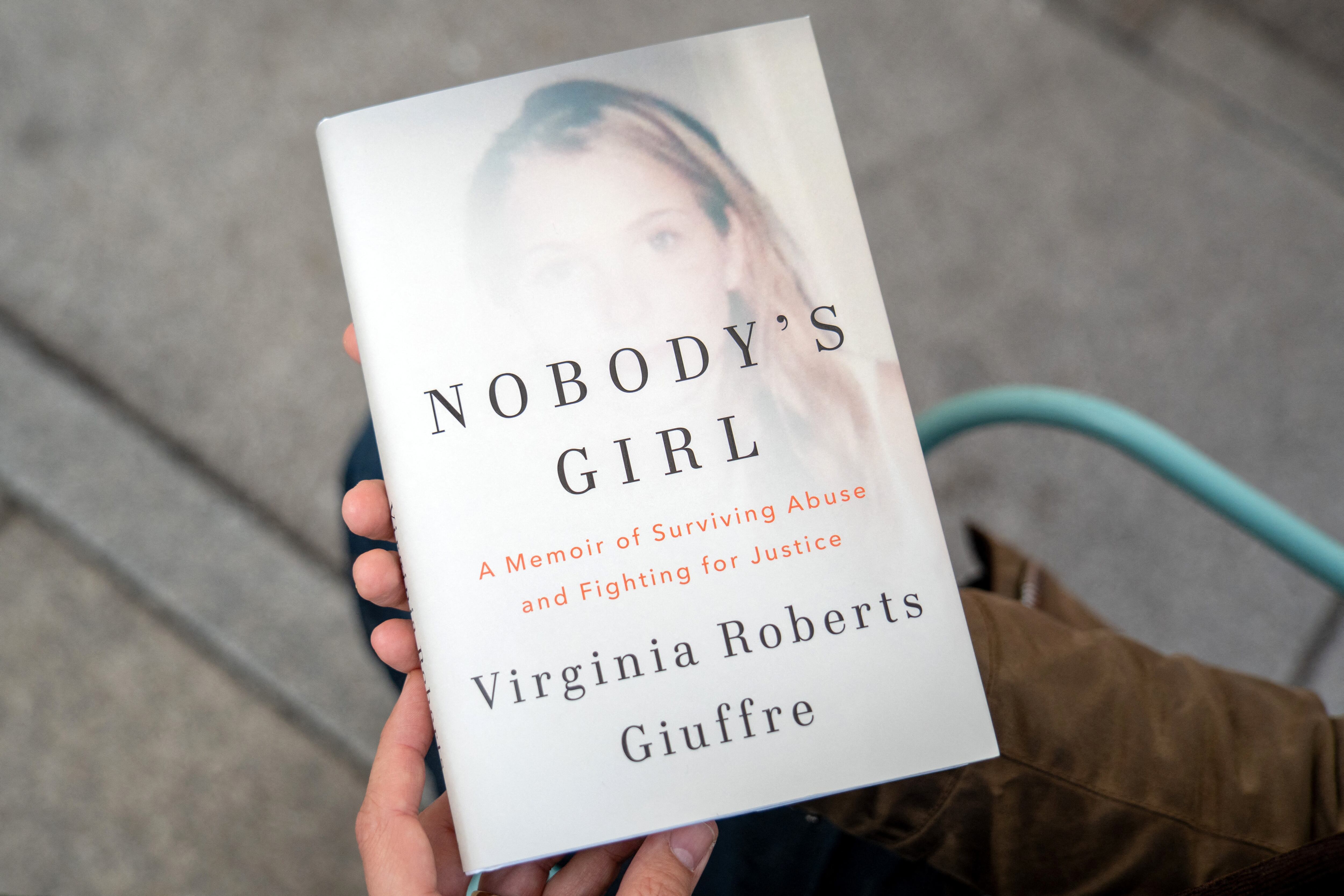 Una persona posa para una foto con un ejemplar del libro "Nobody's Girl - A Memoir of Surviving Abuse and Fighting for Justice" de Virginia Roberts Giuffre, en el centro de Londres el 21 de octubre de 2025. (Foto de Niklas HALLE'N / AFP).