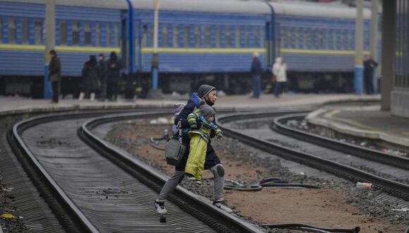 Una mujer cruza las vías con un bebe en brazos para intentar subir a un tren en dirección a Lviv, en Kiev, Ucrania, el 3 de marzo de 2022. (Foto: AP/Vadim Ghirda)