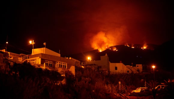El incendio forestal en las colinas sobre las casas, en el valle de Guimar en la isla canaria de Tenerife. (Foto de DESIREE MARTIN / AFP)