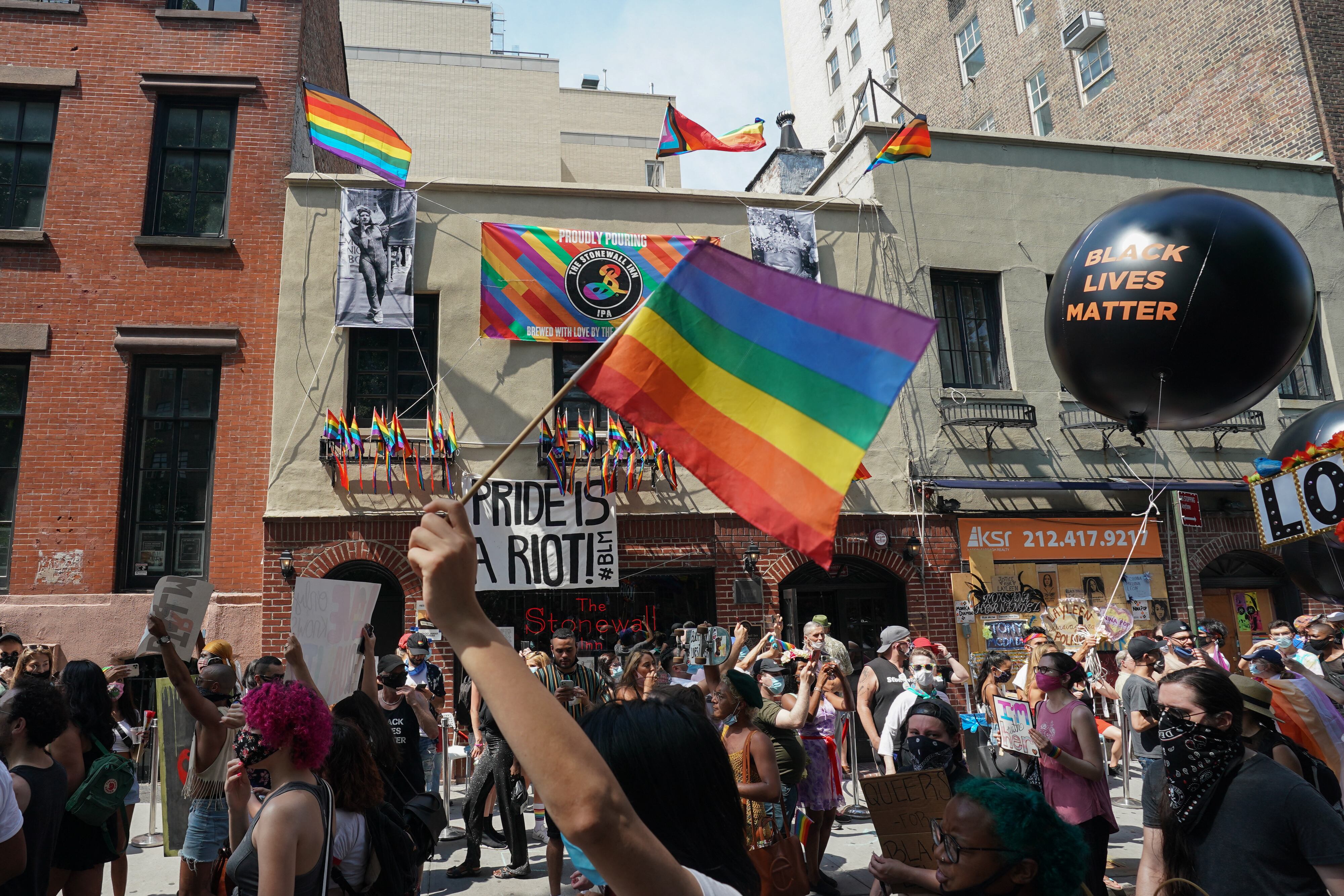 Manifestantes con carteles pasan frente al Stonewall Inn durante la Marcha de Liberación Queer organizada por The Reclaim Pride Coalition for Trans and Queer black lives and against brutality policial en el bajo Manhattan el 28 de junio de 2020 en Nueva York. (Foto de Bryan R. Smith / AFP)