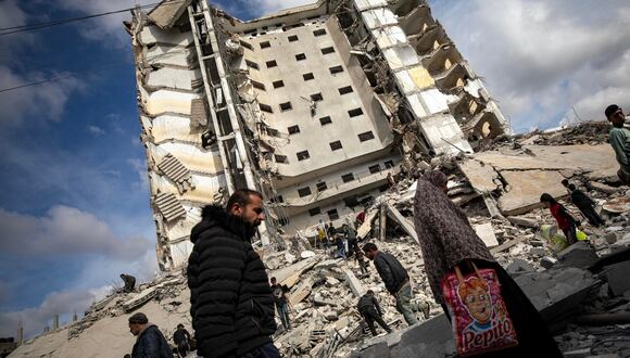os palestinos caminan mientras otros inspeccionan la zona después de un ataque aéreo israelí que golpeó la Torre Al-Masry (fondo del edificio) en el campo de refugiados de Rafah, en el sur de la Franja de Gaza, el 9 de marzo de 2024. EFE/EPA/HAITHAM IMAD