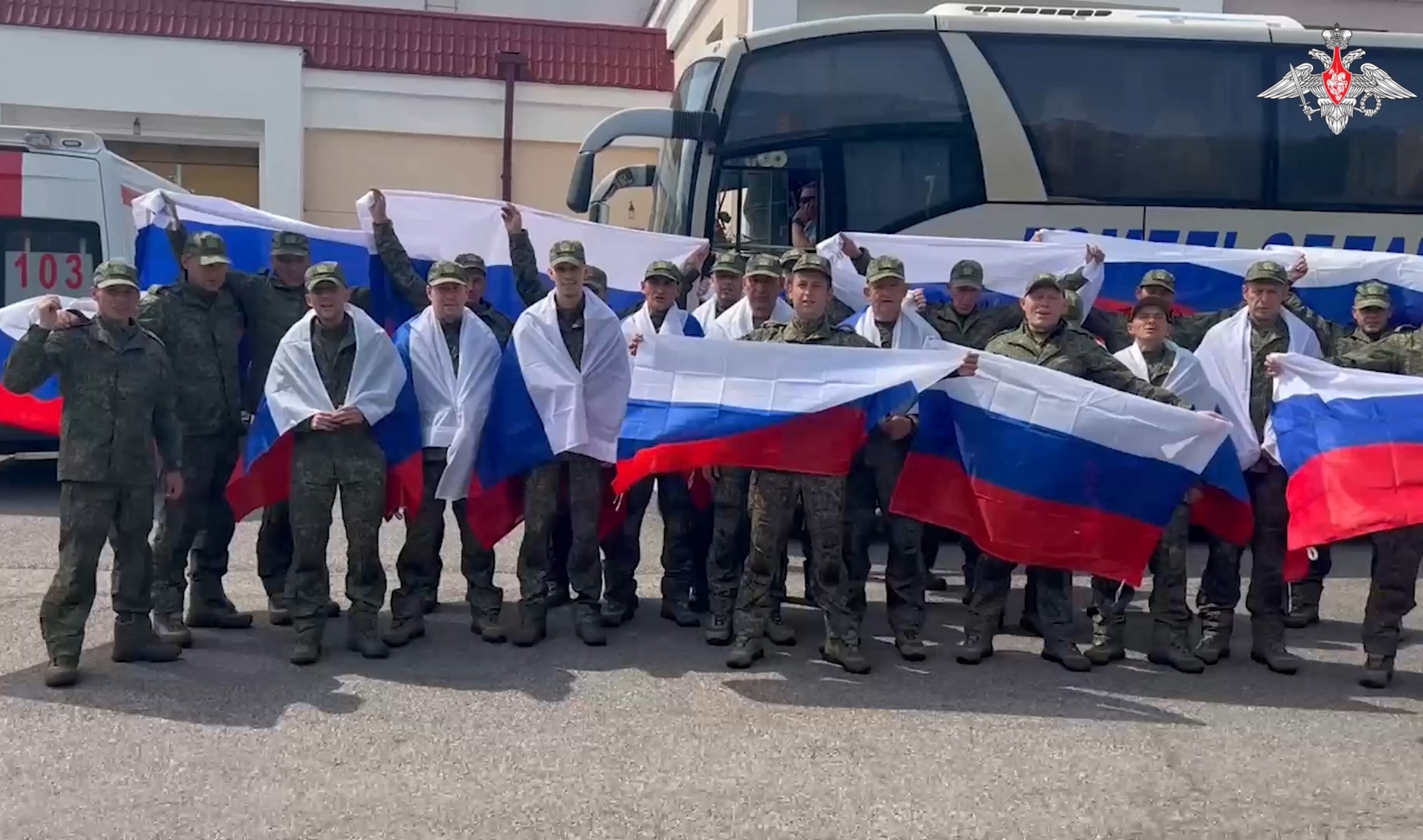 prisioneros de guerra rusos portando banderas nacionales rusas mientras posan para una fotografía tras un intercambio de prisioneros en un lugar no revelado de Bielorrusia. (Foto de Ministerio de Defensa ruso / AFP)