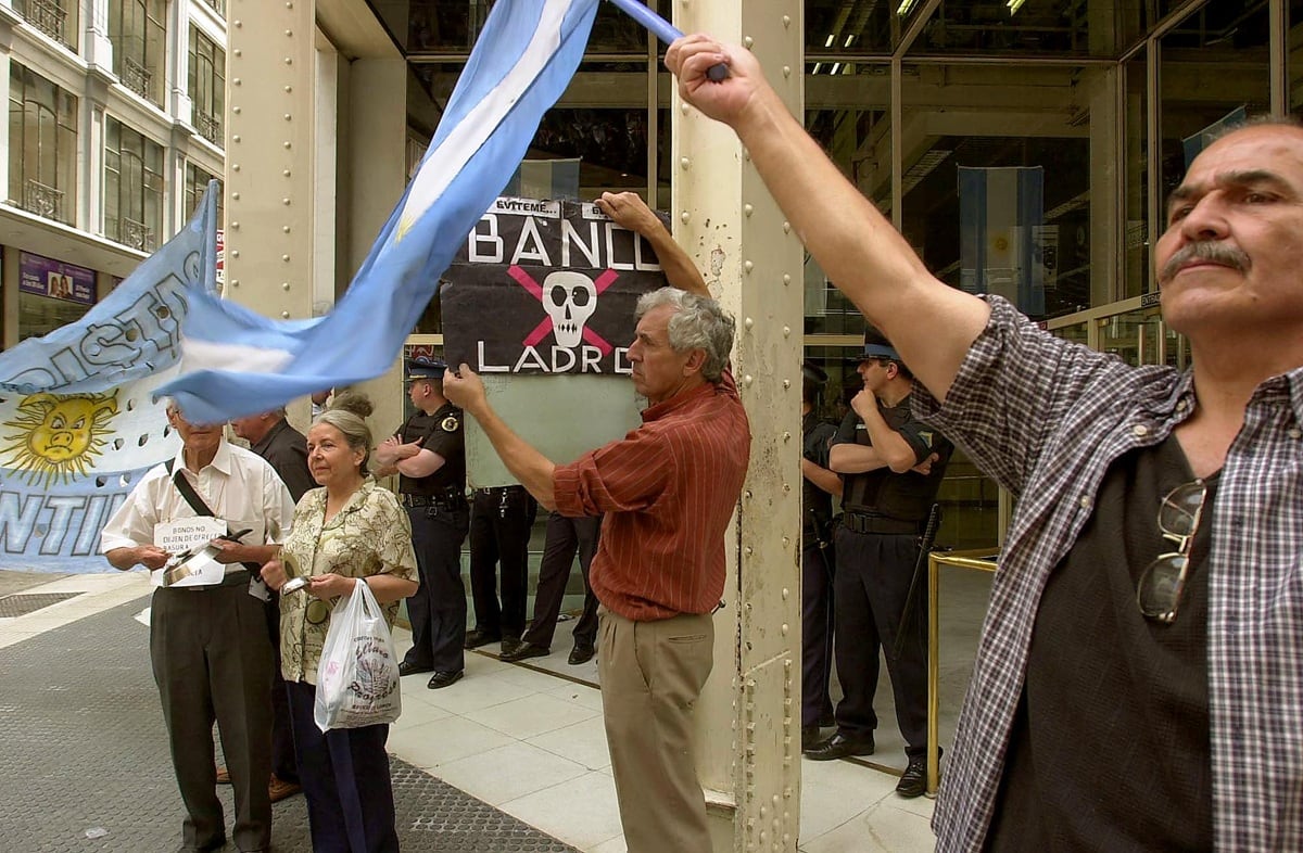Varias personas se manifiestan en la puerta de un banco de Buenos Aires, Argentina, tras el levantamiento del corralito bancario, el 2 de diciembre de 2002. (Foto de MARTIN ZABALA / DYN / AFP)
