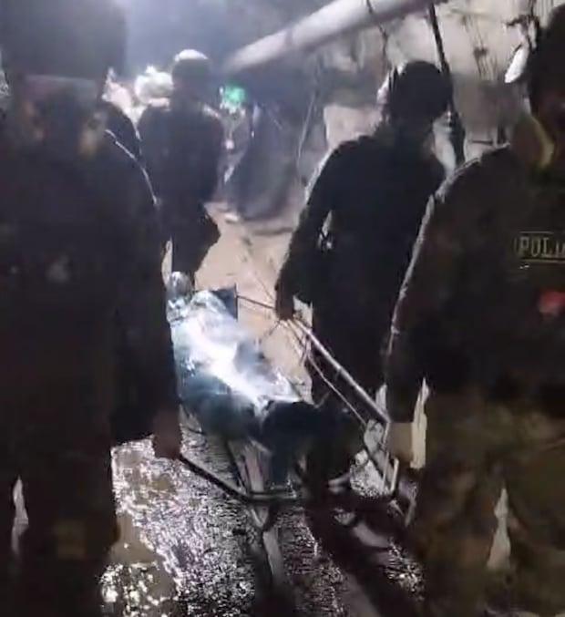 Policías retiran un cuerpo encontrado en la fosa.