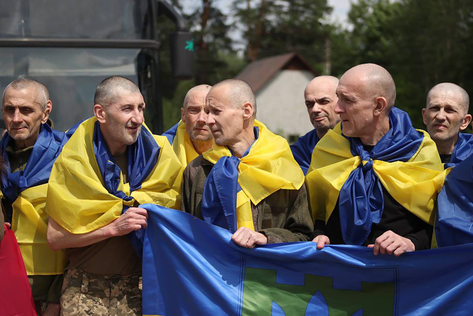 Prisioneros de guerra ucranianos, envueltos en banderas nacionales ucranianas, posando para una fotografía tras un intercambio de prisioneros en un lugar no revelado de Ucrania, en medio de la invasión rusa. (Foto de SERVICIO DE PRENSA PRESIDENCIAL DE UCRANIA / AFP)