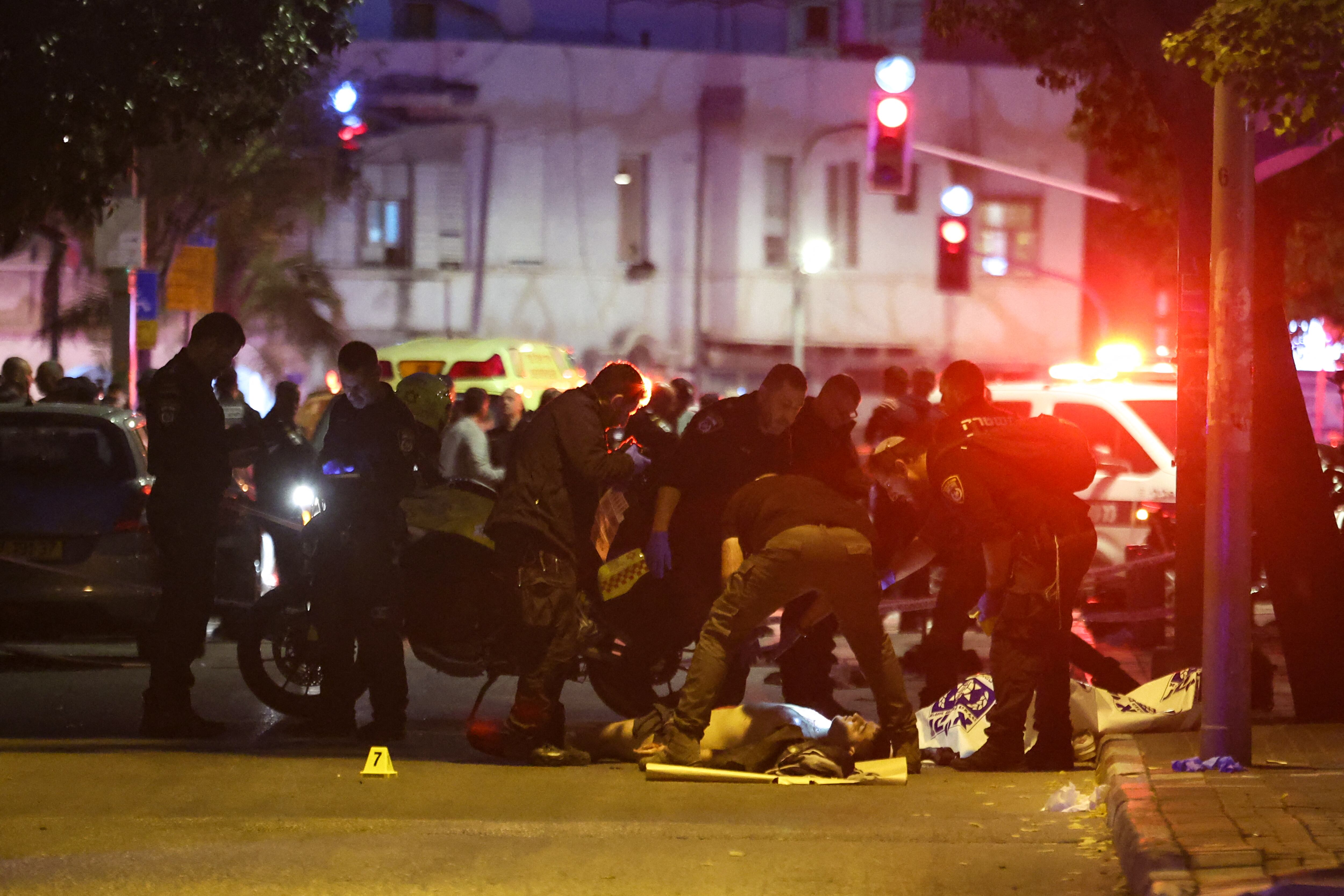 La policía israelí inspecciona el cuerpo del presunto agresor en el lugar de un ataque con arma blanca en Tel Aviv el 18 de enero de 2025, un día antes de que entre en vigor un alto el fuego en Gaza tras la aprobación por parte del gabinete israelí de un acuerdo entre Israel y Hamás. (Foto de Jack GUEZ / AFP)
