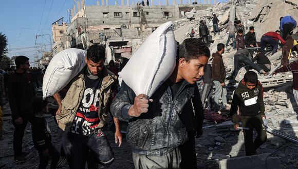 Los palestinos se van con algunos artículos rescatados de los escombros de un edificio residencial alcanzado durante un ataque aéreo israelí nocturno en Rafah, en el sur de la Franja de Gaza, el 9 de marzo de 2023, en medio de continuas batallas entre Israel y el grupo militante palestino Hamas. (Foto de SAID KHATIB / AFP)