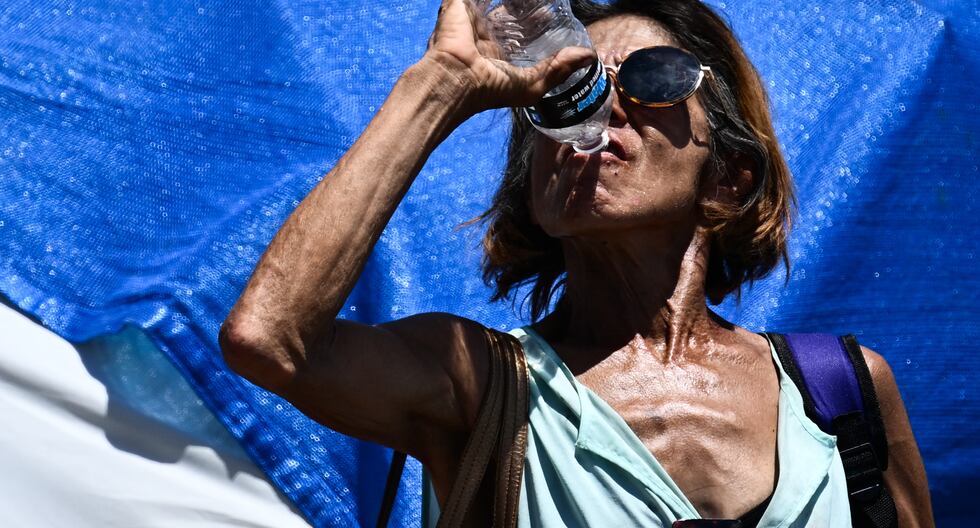 Una persona bebe una botella de agua mientras camina por "La Zona", un enorme campamento de personas sin hogar donde residen cientos de personas, durante una ola de calor récord en Phoenix, Arizona. (Foto: AFP)