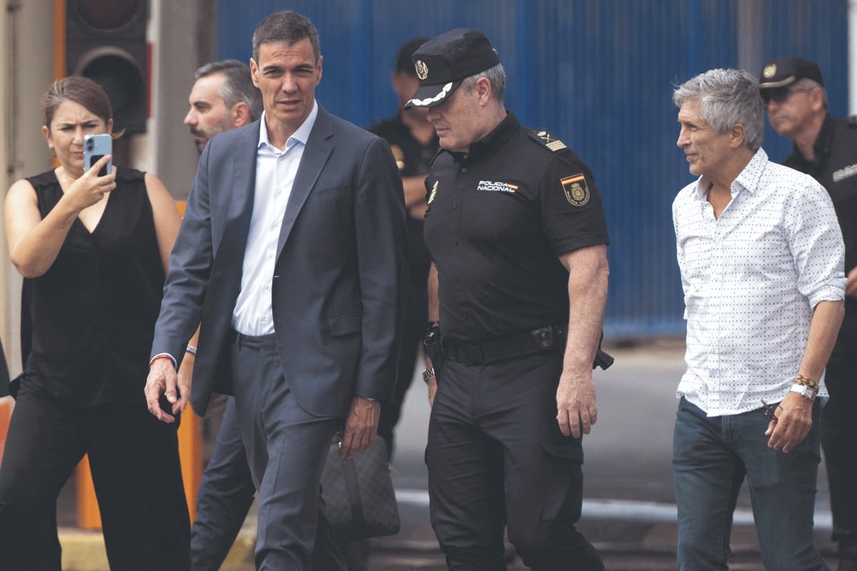 El presidente del Gobierno de España, Pedro Sánchez (centro), y el ministro del Interior, Fernando Grande-Marlaska (derecha), caminan junto a la valla fronteriza de El Tarajal —que separa el enclave español de Ceuta, en el norte de África, de Marruecos— durante una visita para gestionar una de las mayores crisis migratorias en la frontera del país, tras el cruce masivo de miles de migrantes desde Marruecos durante la noche del 31 de julio de 2026. (FOTO DE JORGE GUERRERO / AFP)
