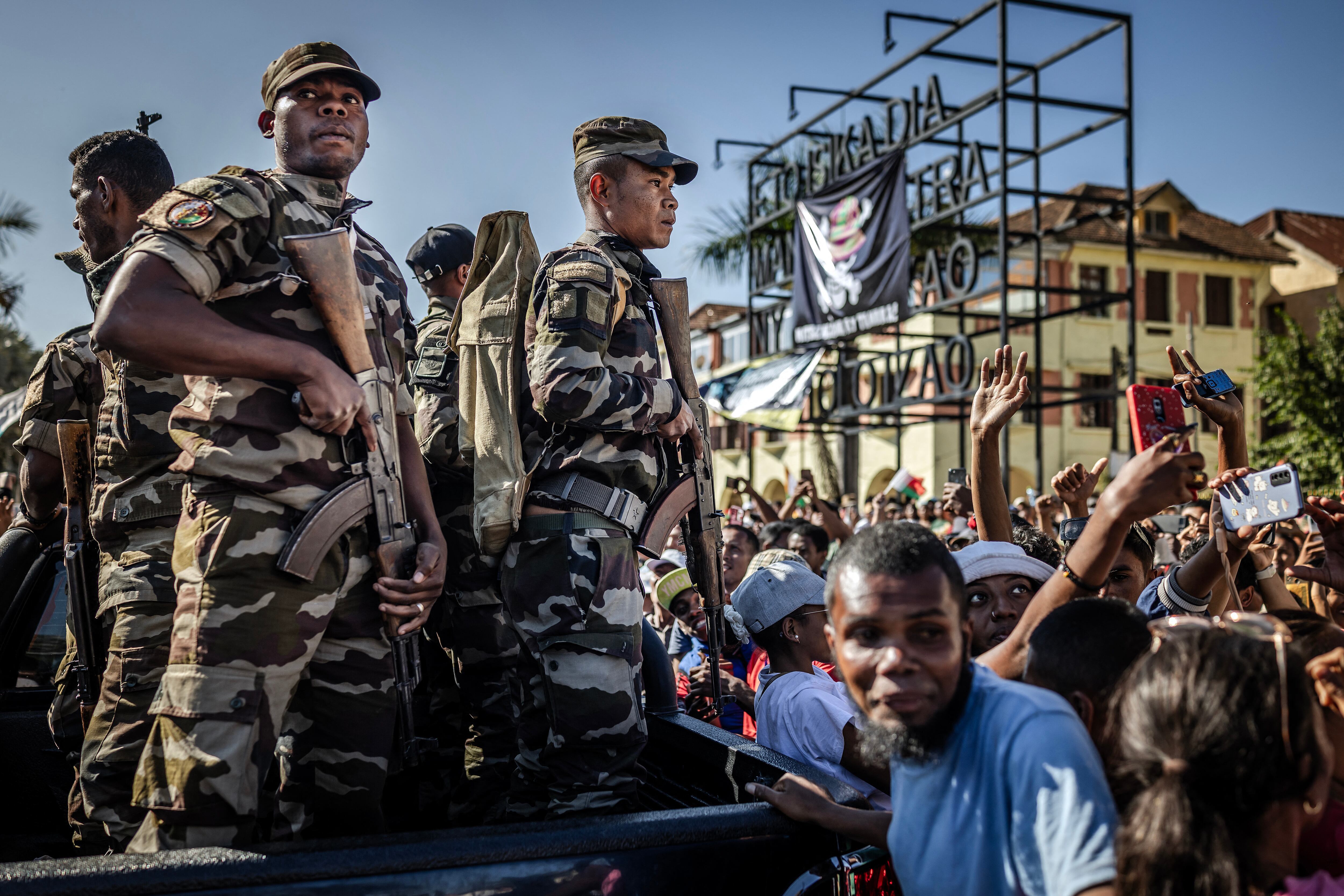 Miembros de la unidad CAPSAT del Ejército de Madagascar, rodeados de jóvenes manifestantes que se toman selfis, pasan junto a una protesta de la sociedad civil que exige la dimisión del presidente Andry Rajoelina. (Foto de Luis TATO / AFP).