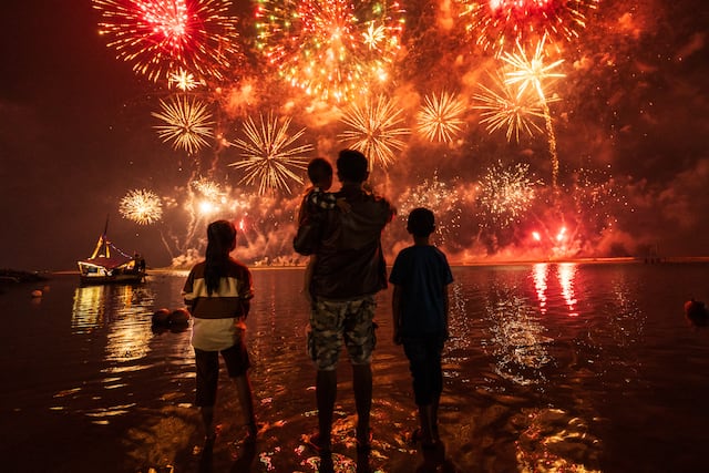 Los residentes locales miran los fuegos artificiales mientras celebran el Año Nuevo en la playa de Ancol, en Yakarta, el 1 de enero de 2025. (Foto de Yasuyoshi CHIBA / AFP).