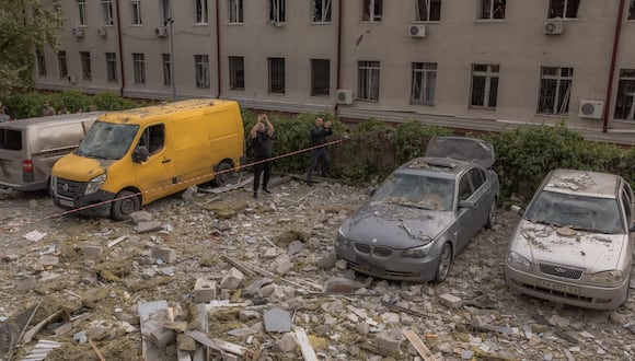 Hombres se encuentran entre los escombros frente a un edificio residencial dañado como resultado de un ataque con misiles en Kharkiv. (Foto de Román PILIPEY / AFP)