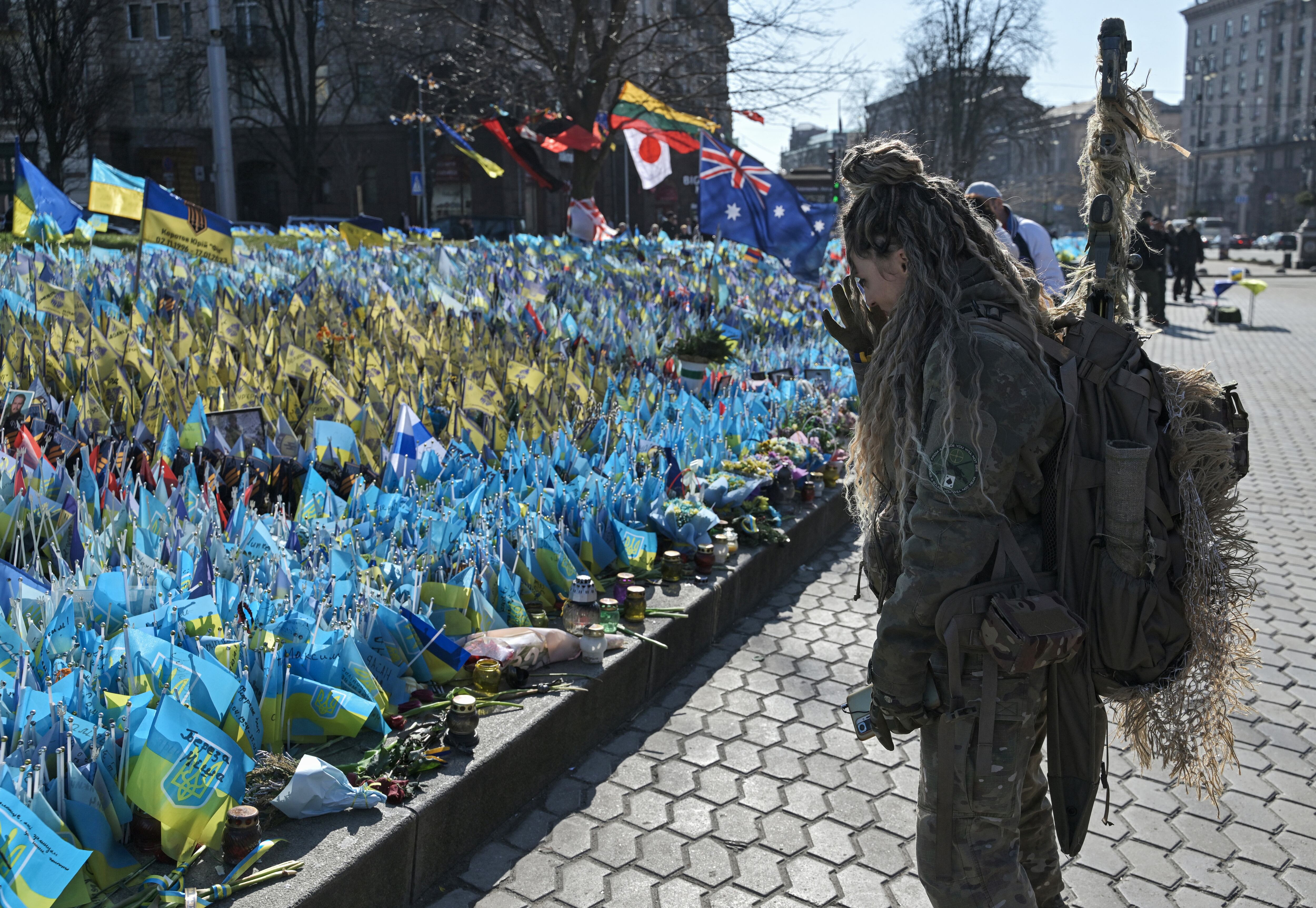 Una militar ucraniana se encuentra frente a un monumento improvisado para los soldados ucranianos caídos en la Plaza de la Independencia en el Día Internacional de la Mujer en Kiev, el 8 de marzo de 2024, en medio de la invasión rusa de Ucrania. (Foto de Genya SAVILOV / AFP)