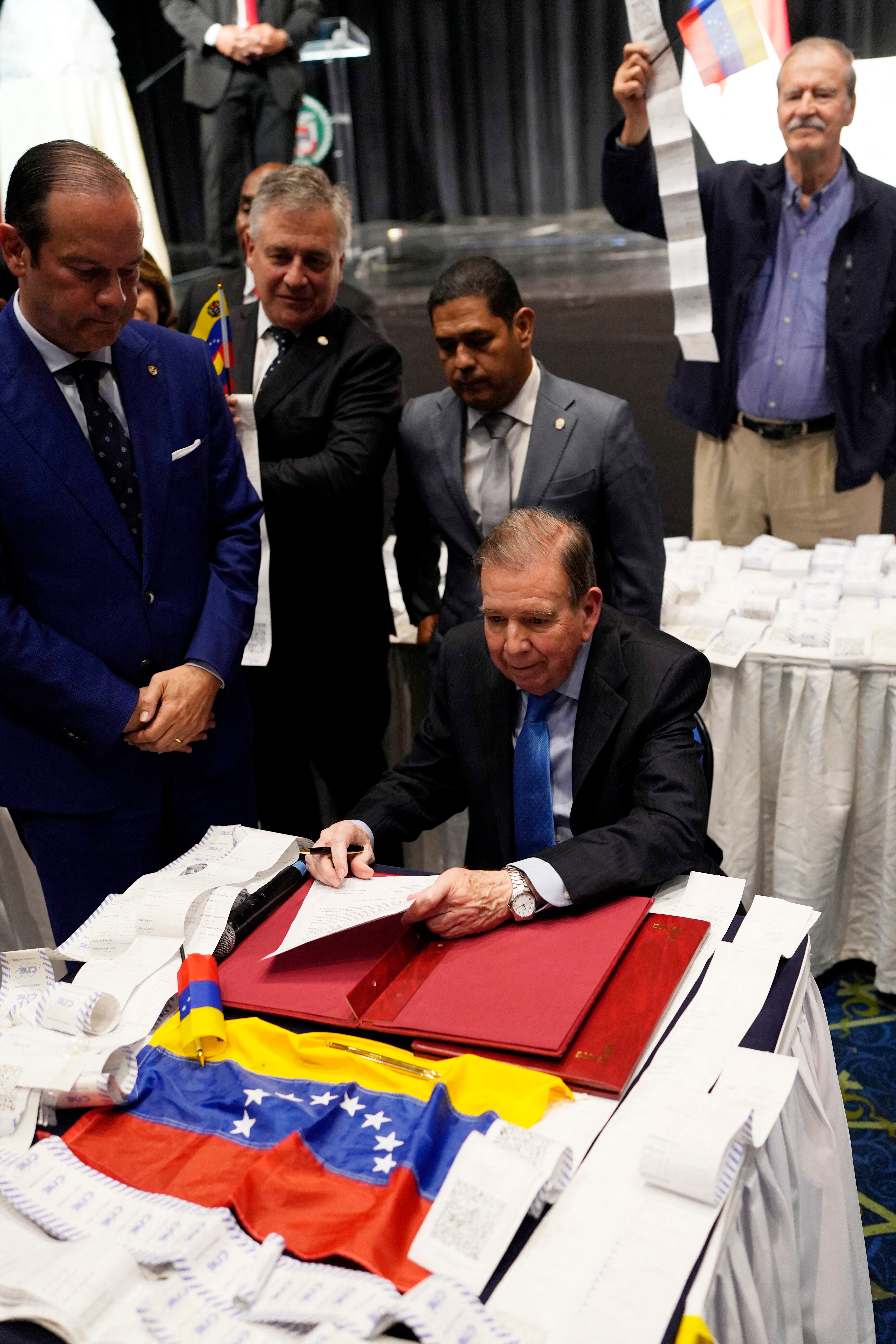 El líder opositor venezolano Edmundo González Urrutia (centro) sostiene un documento junto a los registros de votación mientras el ministro de Relaciones Exteriores de Panamá, Javier Martínez Acha (izq.), lo mira durante el Acto de Reafirmación de la Democracia con Venezuela en el centro de convenciones Atlapa en la Ciudad de Panamá el 8 de enero de 2025. (Foto de ARNULFO FRANCO / AFP)
