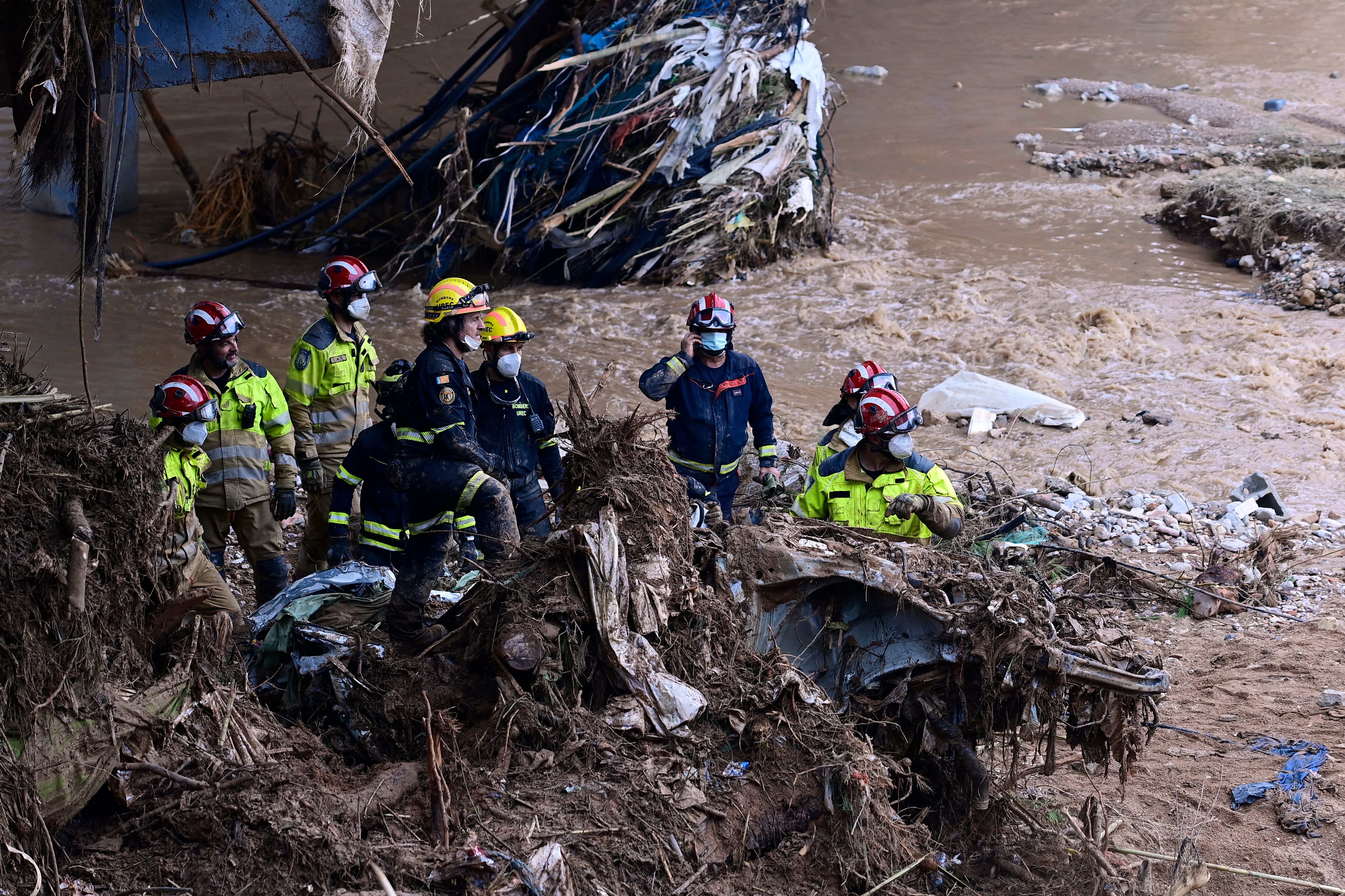 Los bomberos retiran los escombros de un automóvil enterrado en la orilla de un río en Paiporta, en la región de Valencia, este de España, el 3 de noviembre de 2024, tras las devastadoras inundaciones. (Foto de JOSE JORDAN / AFP)
