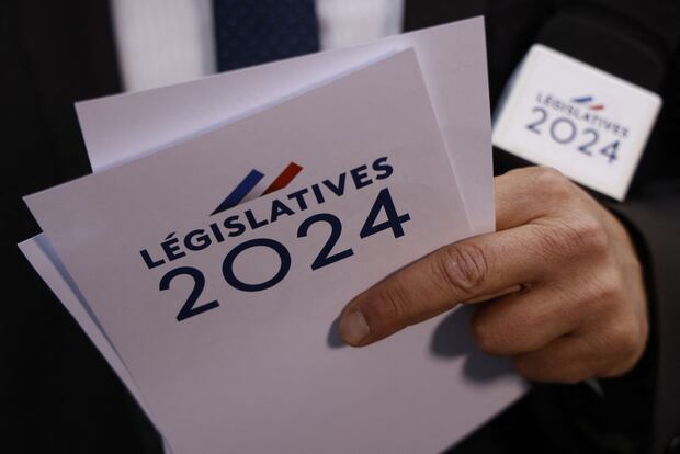 A journalist holds the marked cards "Legislature 2024" in Paris on June 30, 2024.  (Photo by Ludovic MARIN / AFP).
