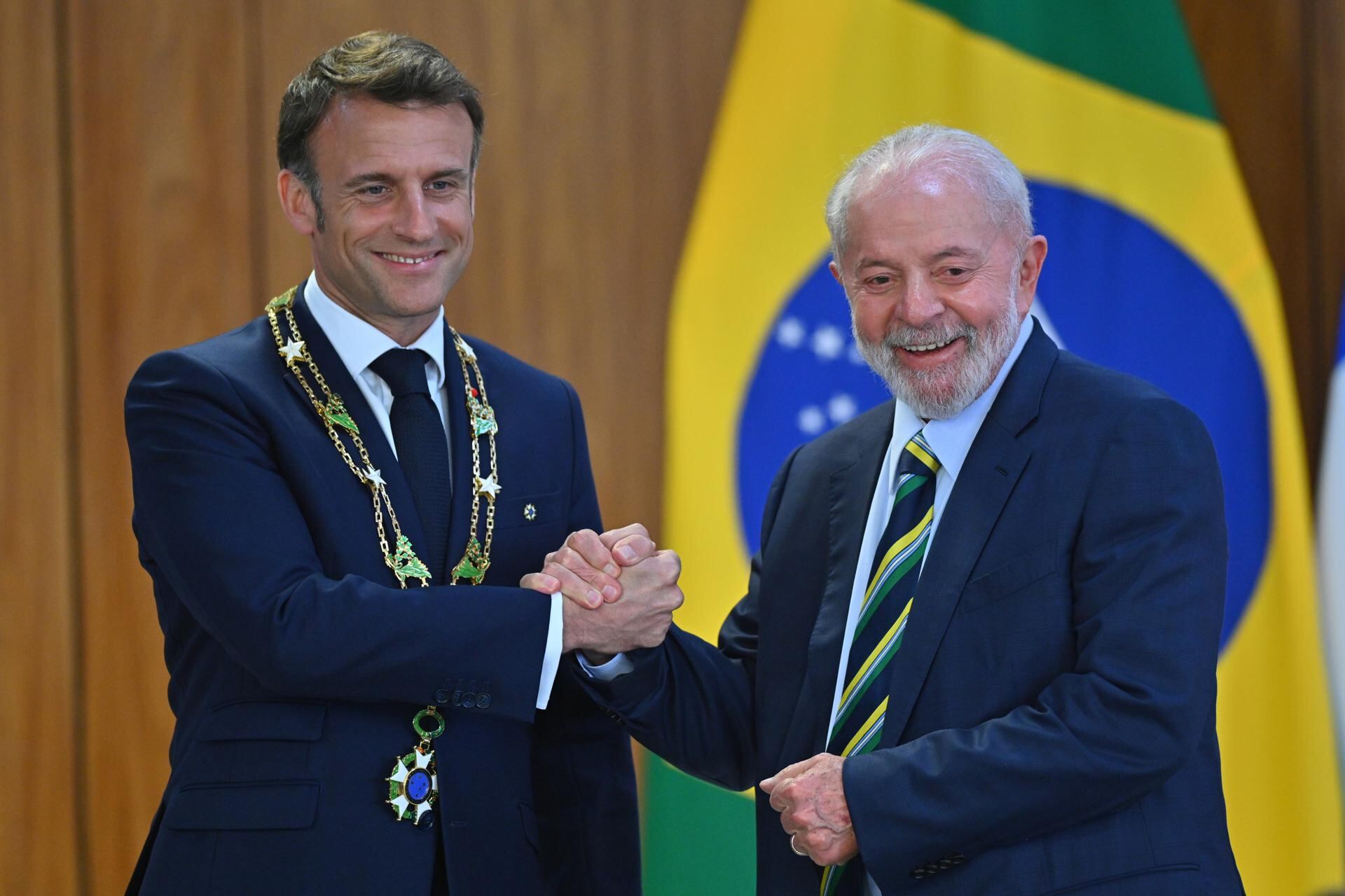 El presidente de Brasil, Luiz Inácio Lula da Silva, condecora al presidente de Francia, Emmanuel Macron, durante una ceremonia este jueves, en el Palacio del Planalto. (EFE/Andre Borges).