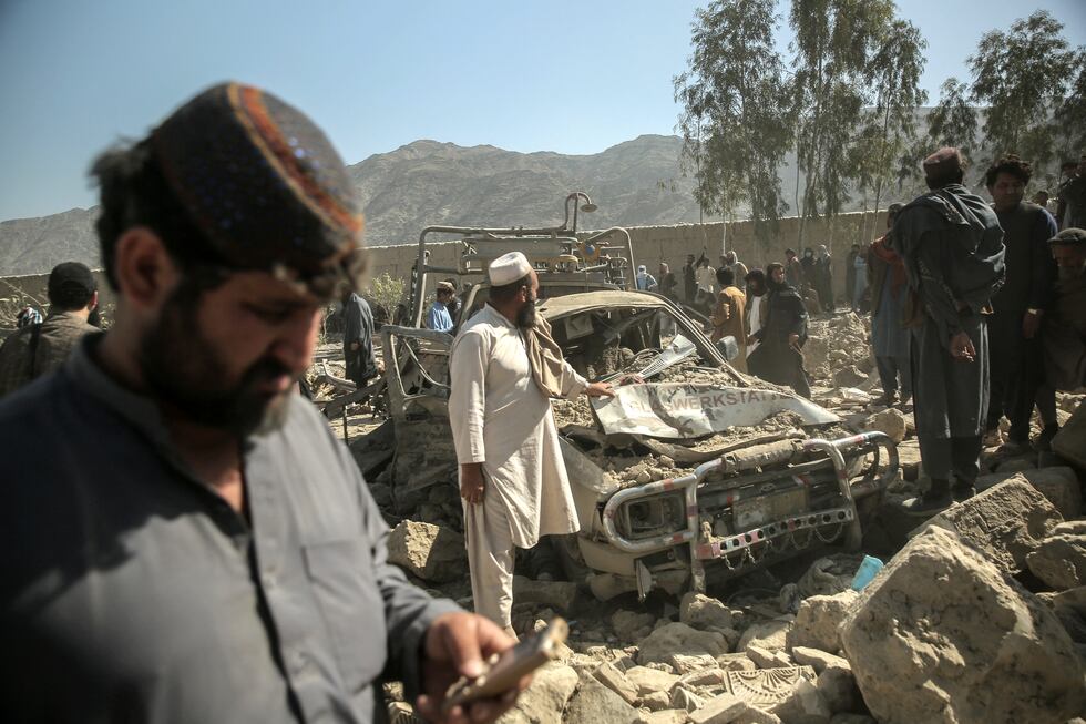 Hombres afganos se reúnen cerca de un coche dañado tras un ataque aéreo de Pakistán que impactó una zona residencial en la aldea de Girdi Kas, en el distrito de Bihsud, provincia de Nangarhar, el 22 de febrero de 2026. (Foto de AFP).