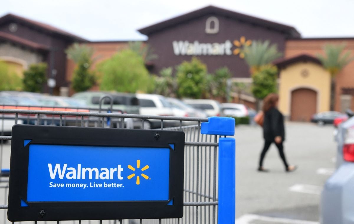 Una mujer pasa junto a un carrito de compras en el estacionamiento de un Walmart. (Foto: AFP)