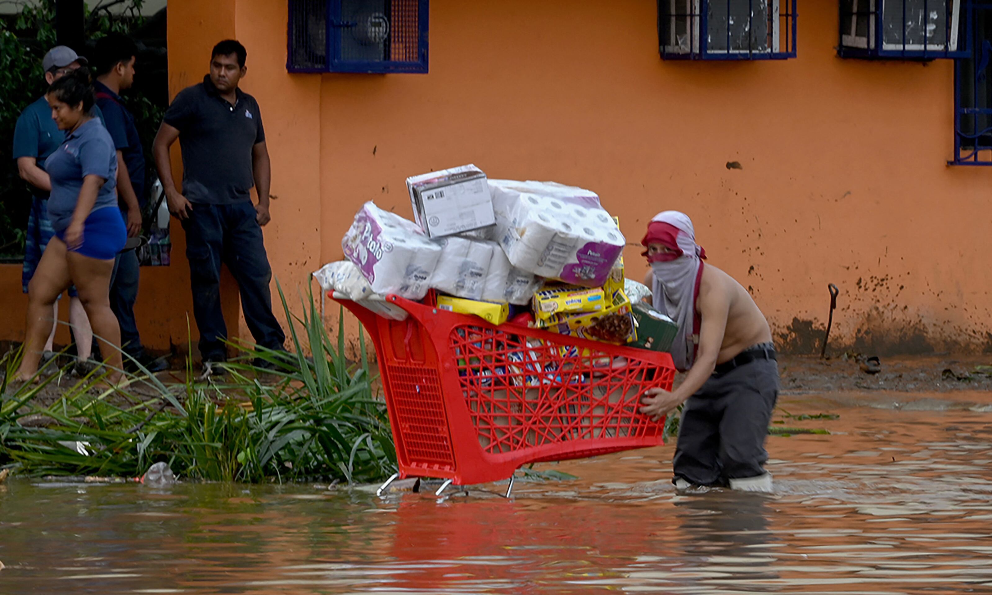 Un saqueador lleva un carrito lleno de bienes robados de un supermercado tras el paso del huracán Otis en Acapulco. (Foto de FRANCISCO ROBLES/AFP).