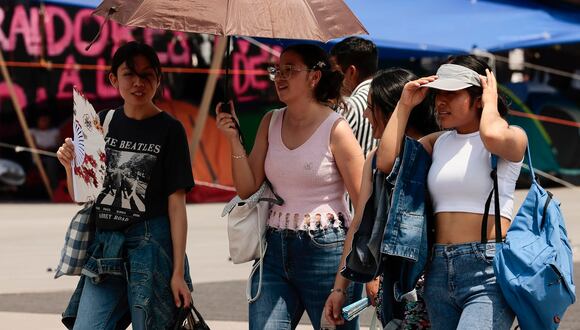 Varias personas caminan con sombrilla para protegerse del sol, este viernes en Ciudad de México (México). EFE/José Méndez