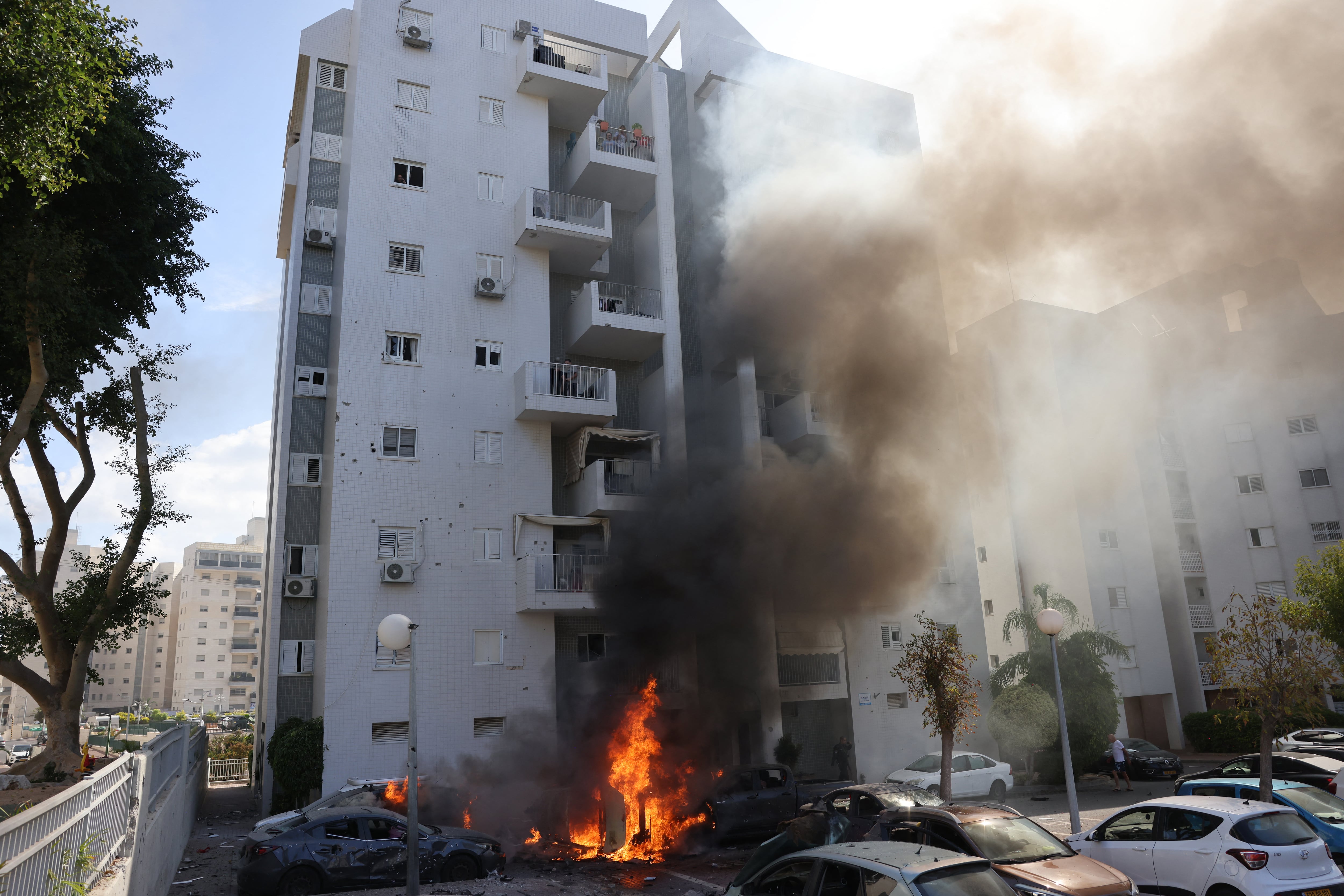Los coches estacionados frente a un edificio residencial se incendian durante un ataque con cohetes desde la Franja de Gaza contra la ciudad de Ashkelon, en el sur de Israel, el 7 de octubre de 2023. (Foto de AHMAD GHARABLI / AFP)