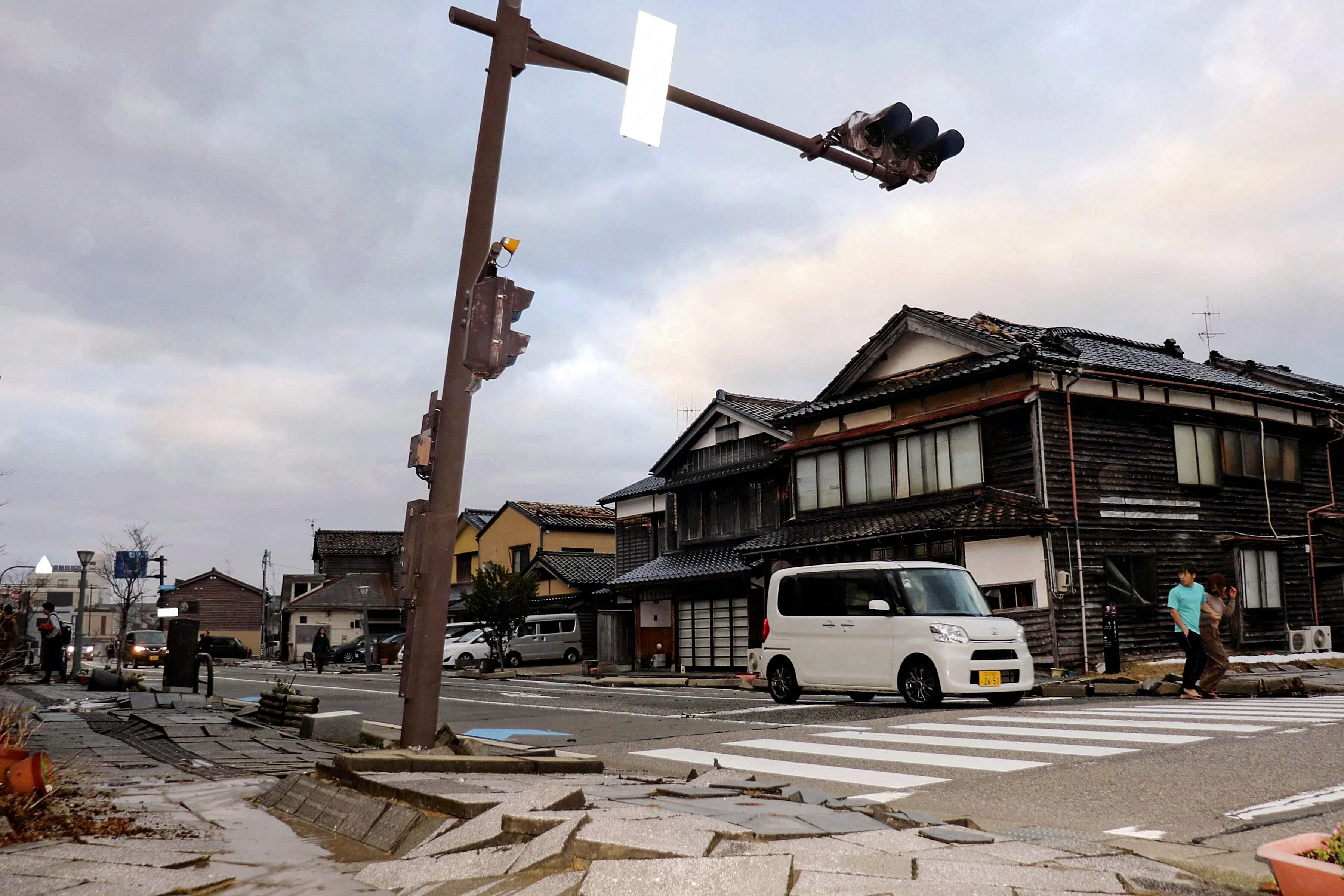 Un automóvil pasa por una acera muy dañada a lo largo de una calle de la ciudad de Wajima, prefectura de Ishikawa, el 1 de enero de 2024, después del terremoto. (Foto de Yusuke FUKUHARA / Yomiuri Shimbun / AFP).