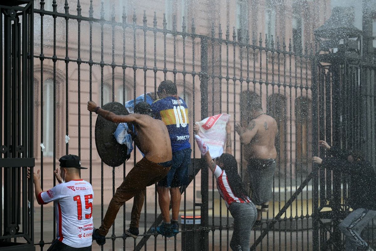 Manifestantes trepan una valla frente al palacio presidencial Casa Rosada durante una protesta de jubilados apoyados por barrabravas contra el gobierno del presidente Javier Milei en Buenos Aires, el 12 de marzo de 2025. (Foto de Luis ROBAYO / AFP)