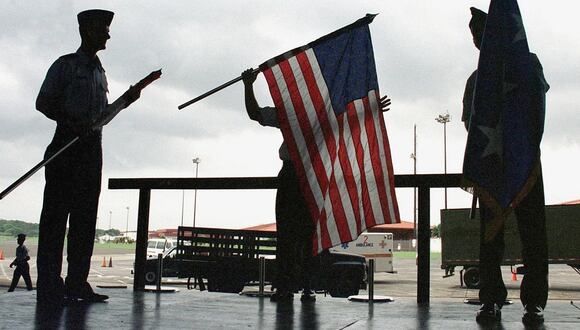 Personal de la Fuerza Aérea de EE. UU. dobla banderas estadounidenses mientras se prepara para abandonar la Base de la Fuerza Aérea Howard en la Zona del Canal de Panamá, el 3 de junio de 1999. (Foto de DEMOSTENES ANGEL / AFP)